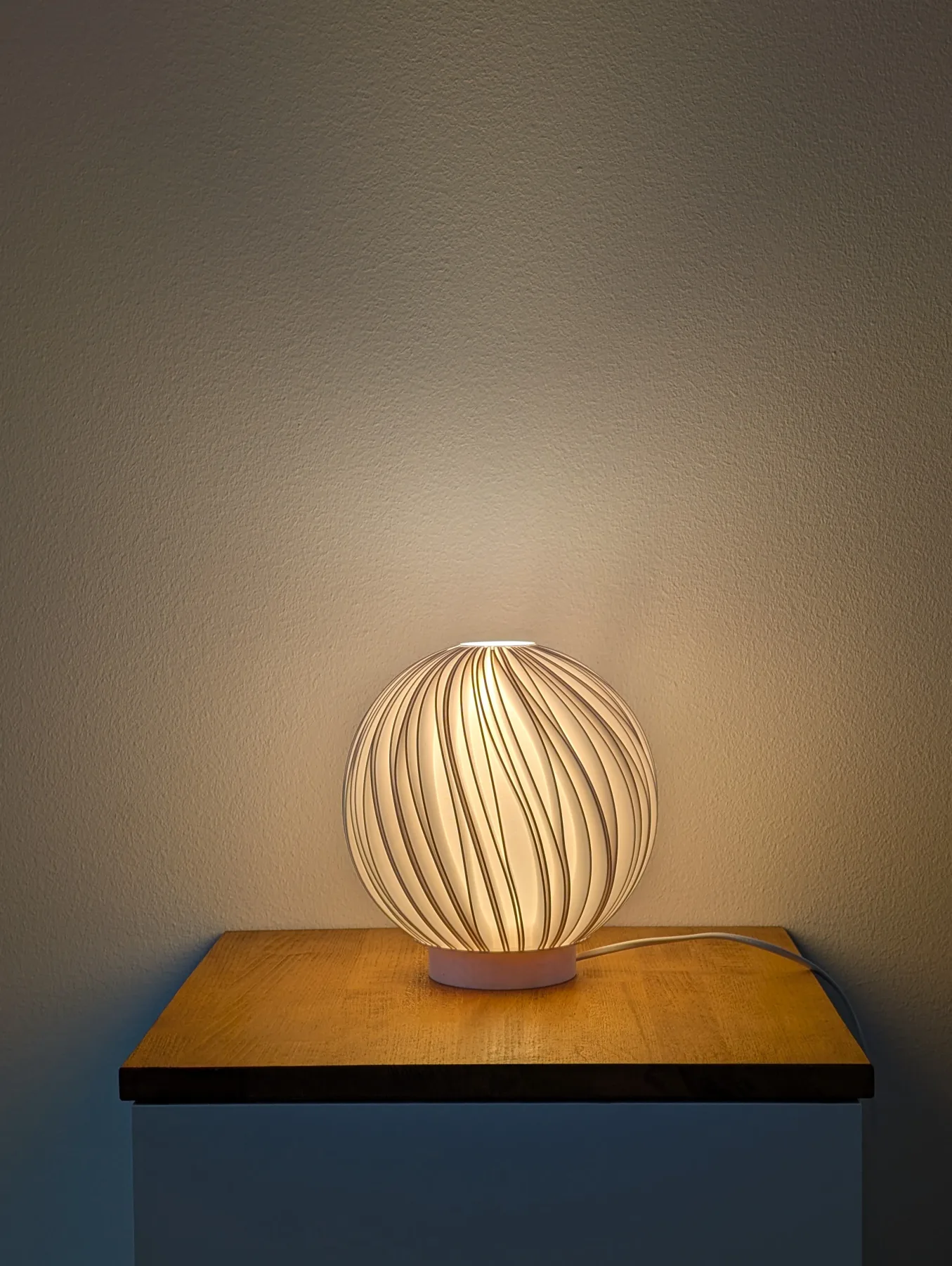 Rima Mellem lamp glowing warm on a nightstand in the evening