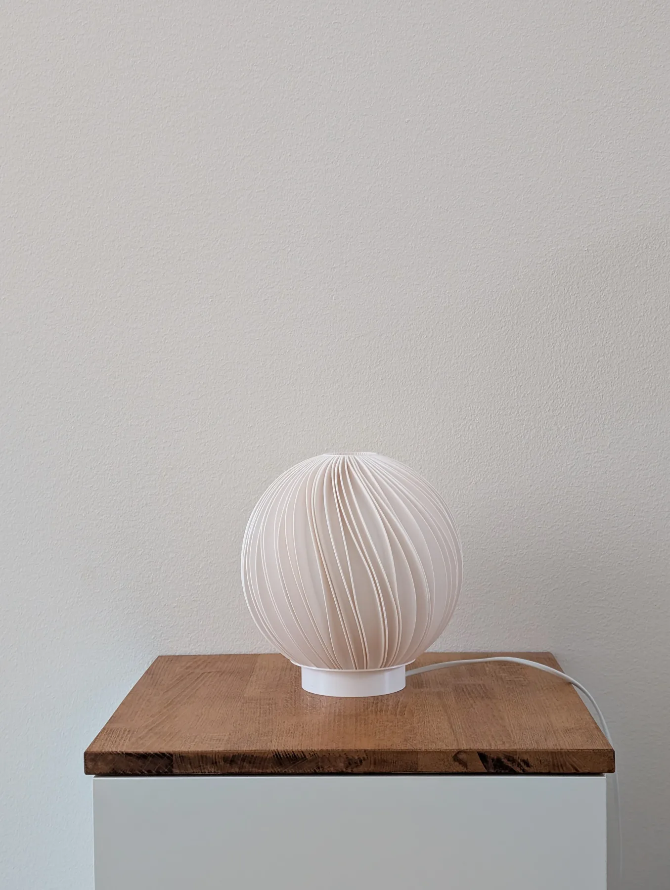 Rima Mellem lamp unlit on a nightstand against a plain wall